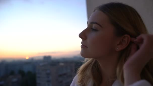 Mulher ajustando o cabelo olhando para o pôr do sol da varanda desfrutando paisagem urbana, meditar — Vídeo de Stock