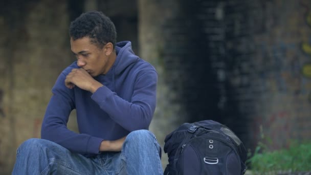 Herido tosiendo niño varón sentado en la calle cerca de la mochila, corriendo de casa — Vídeos de Stock