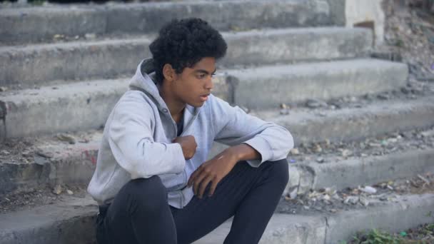 Депрессивный молодой черный мужчина сидит снаружи, эмоциональное насилие, семейные проблемы — стоковое видео