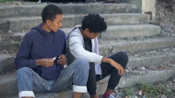 Needy young men counting coins sitting stairs, dysfunctional family children — Stock Video