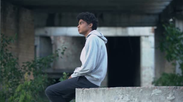 憂うつな孤独な黒人男性座って放棄された建物の問題を考える — ストック動画