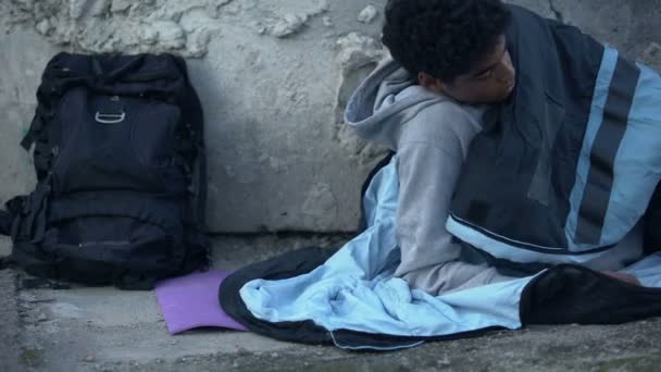 Молодой мужчина застегивает спальный мешок, засыпает на улице, бежит домой, кризис — стоковое видео