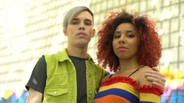 Renkli giyinmiş, fotoğraf makinesi takılan bir çift piercing 'li genç.