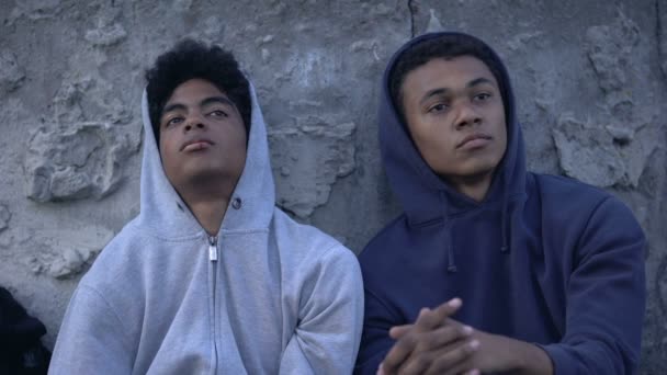 Грустные старшеклассники склоняются к цементной стене, низкий уровень жизни, бедность — стоковое видео