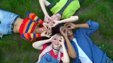 Dürbün gibi güzel hareketler yapan mutlu gençler kampüs parkında çimenler uzanıyor.