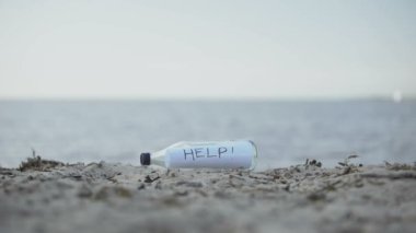 Word Help in glass bottle lying on beach, mystery message of shipwreck survivors