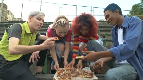 Молодые счастливые люди едят пиццу на открытом воздухе, друзья отдыхают вместе на открытом воздухе — стоковое видео