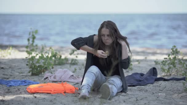 Fagyasztott éhes nő kenyeret eszik a parton, hajótörött menekült túlélő. — Stock videók
