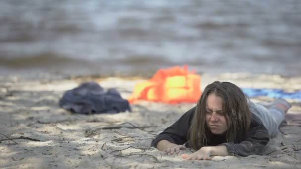 Miserable woman lying on shore, feeling unwell, shipwreck refugee survivor — Stock Video