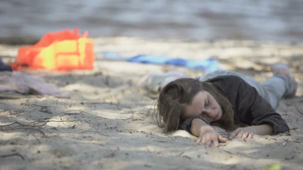 Woman coughing breathing hard, lying on beach after shipwreck, asking help — Stock Video