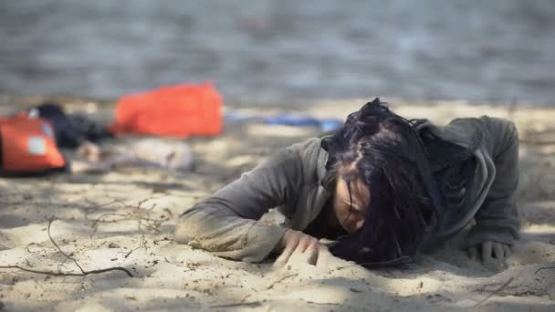 Young woman lying on seashore, breathing hard, feeling unwell after shipwreck — Stock Video