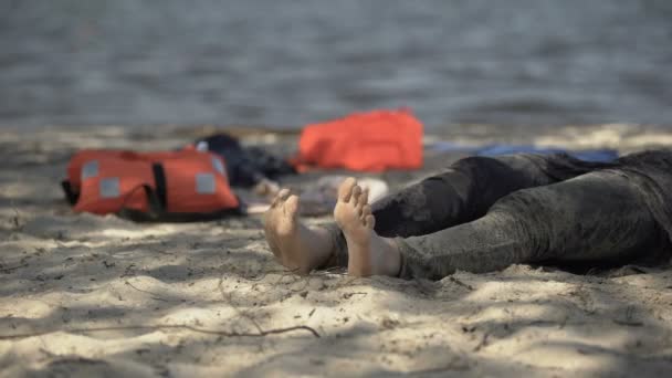 Schlammige Frauenbeine kriechen an Land, Schwimmwesten im Hintergrund, überlebender Sturm — Stockvideo