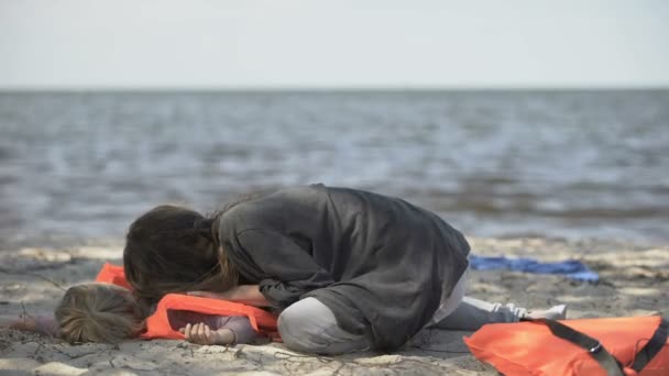 Mother trying to help unconscious daughter in life jacket, shipwreck victims — Stock Video