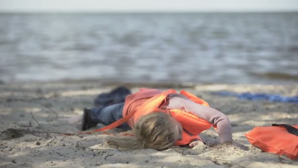 Il bambino rifugiato che si toglie il giubbotto di salvataggio, difficilmente si muove, soffre di dolore dopo il naufragio — Video Stock