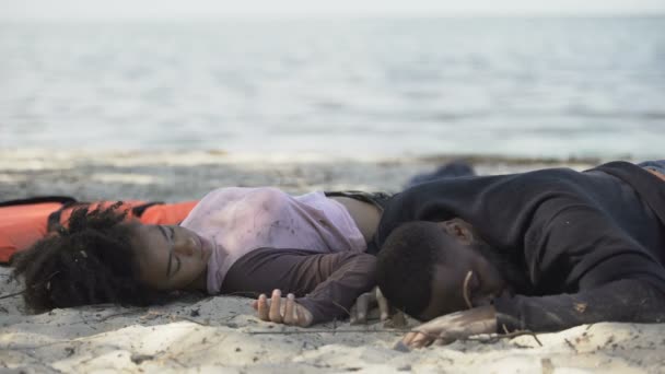 African-american couple lying on shore unconscious, refugees survived shipwreck — Stock Video