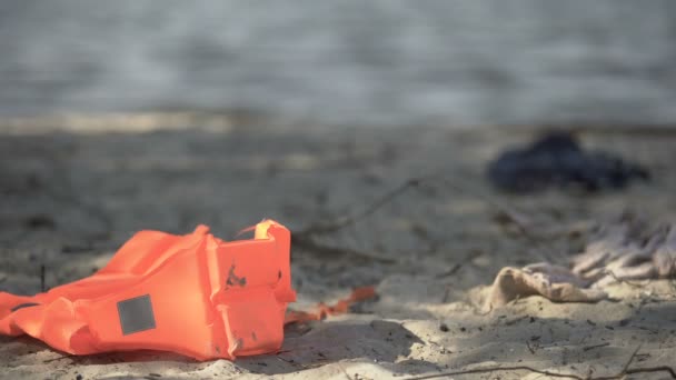 Спасательный жилет, лежащий на берегу моря, зона бедствий, статистика смертности от катастроф — стоковое видео