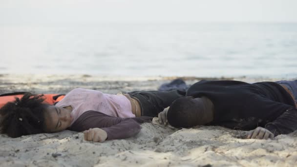 Black man waking on shore lying near unconscious girl, natural disaster victims — Stock Video