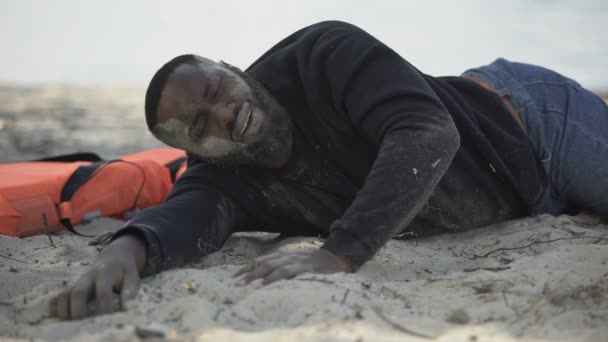 Раненая жертва катастрофы, страдающая болью, лежащая на берегу, пережившая ураган — стоковое видео