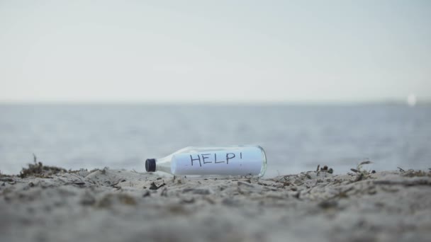 Palabra de ayuda en botella de vidrio tirado en la playa, mensaje misterioso de los sobrevivientes de naufragio — Vídeo de stock