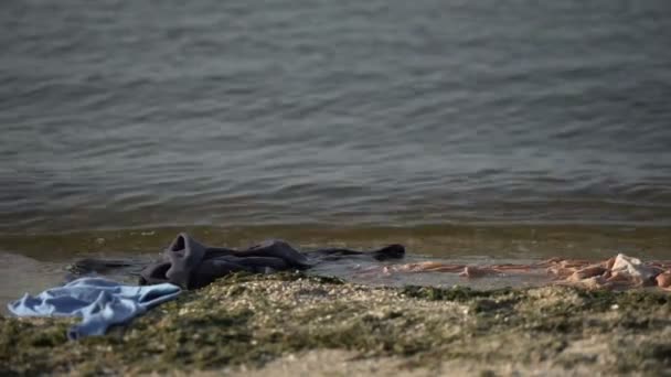 Roupas espalhadas lavadas na água do mar, estatísticas de morte de naufrágios, tsunami — Vídeo de Stock