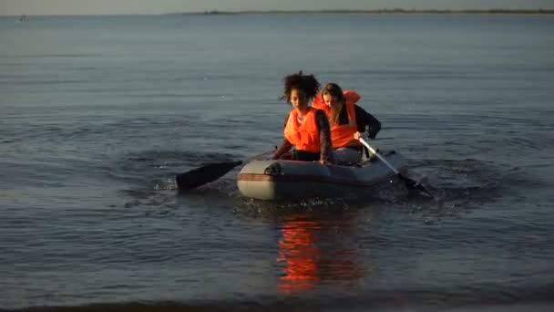 Zwei Frauen in Schwimmwesten rudern Boot, Überlebende der Flut suchen Hilfe an Land — Stockvideo