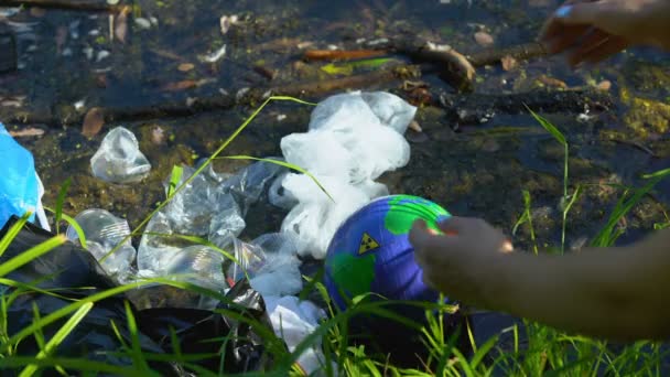 Voluntário levando globo terrestre com sinal de radiação do lago poluído, problema ecológico — Vídeo de Stock