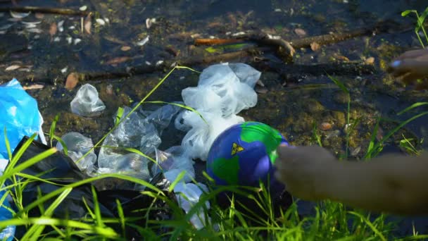 Responsible woman taking Earth globe with biohazard sign from polluted lake — ストック動画