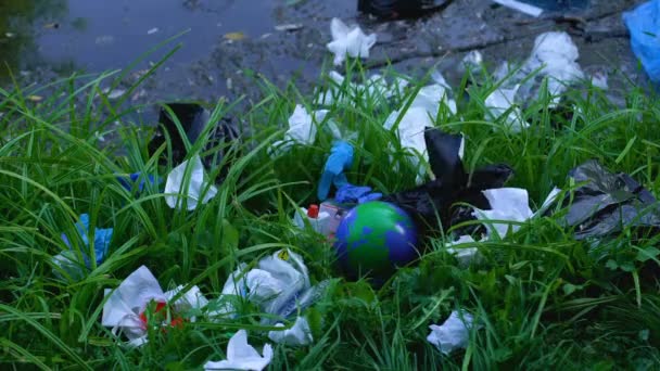 Person throwing Earth globe in landfill near forest lake, ecological pollution — Stock Video