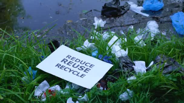Pessoa jogando papelão com reduzir frase reciclagem reutilização na grama poluída — Vídeo de Stock