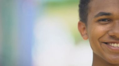 Neşeli melez genç adam kameraya içten bir şekilde gülümsüyor, iyi ruh hali, yarım surat.