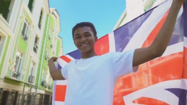 İngiliz bayrağı sallayan ve gülümseyen melez genç adam, ulusal bayram