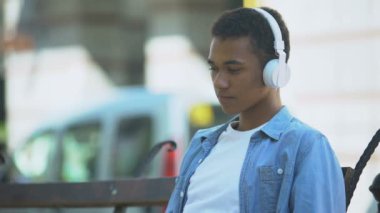 Üzgün melez çocuk, en sevdiği romantik şarkıyı dinliyor, bankta hasret çekiyor.