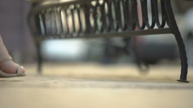 Yüksek topuklu bacaklar ve ortopedik ayakkabılar yüzünden yorgun düşmüş bir kadın bankta dinleniyor.