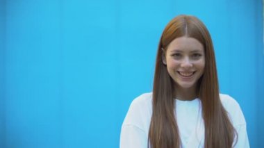 Çekici ve sağlıklı bir kız mavi arka planda gülümsüyor, mutluluk, şablon