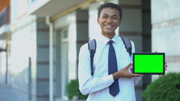 Usmívající se smíšený středoškolák ukazující tablet se zelenou obrazovkou, vzdělávací aplikace — Stock video