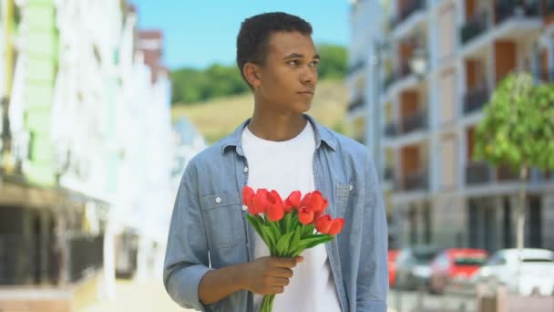 Afro-americano disgustado adolescente masculino con tulipanes enojado por novias tardanza — Vídeos de Stock