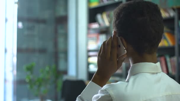 Étudiant afro-américain occupé parlant smartphone, discutant du projet scolaire — Video