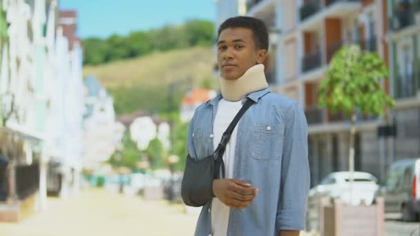 Trieste gemengde ras jongeman in schuim halskraag en arm slinger zuchten op camera — Stockvideo