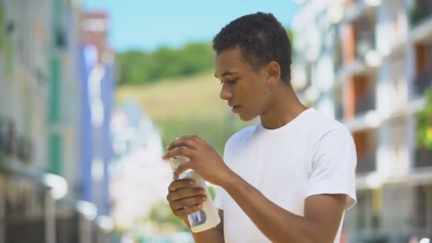 Fatigué sportif adolescent mâle boire de l'eau en bouteille après l'entraînement en plein air actif — Video