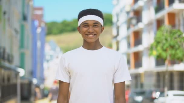 Feliz atleta adolescente de raza mixta con diadema sonriendo en la leva, bienestar y salud — Vídeo de stock