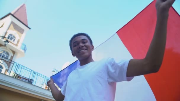 Alegre mestizo masculino adolescente ondeando bandera de Francia y sonriente, fiesta nacional — Vídeos de Stock