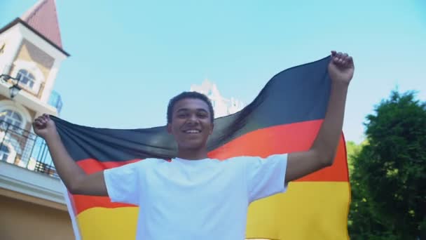 幸せなアフロアメリカのティーン男性手を振ってドイツの旗と笑顔,愛国者行進 — ストック動画