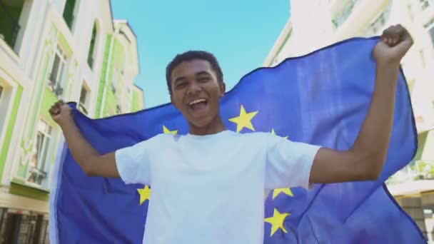 Glada blandras ung man viftar Europeiska unionens flagga utomhus, frihet marsch — Stockvideo