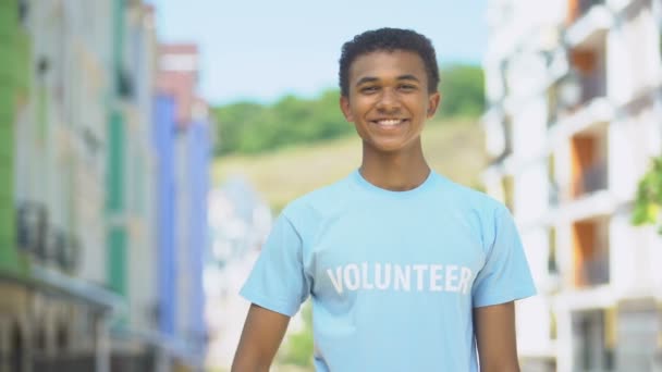 Весёлый афро-американский подросток-волонтер, показывающий большие пальцы вверх и улыбающийся на камеру — стоковое видео