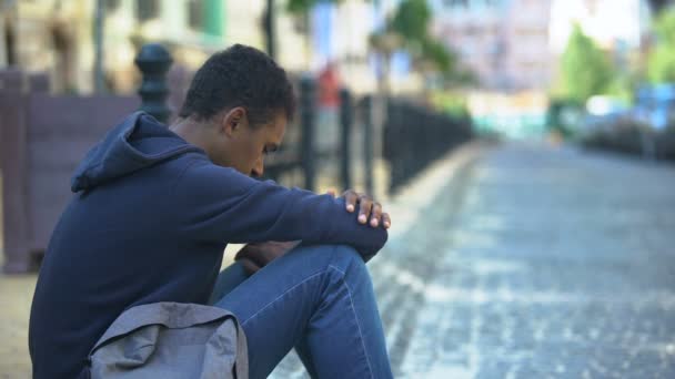 Sad mixed-race teenager sitting on sidewalk, relationship problems, awkward age — Stock Video