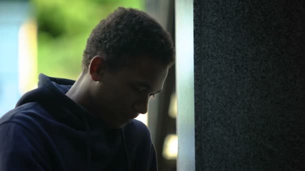 Depressieve Afro-Amerikaanse tiener zitten buiten leunend op de muur, crisis — Stockvideo