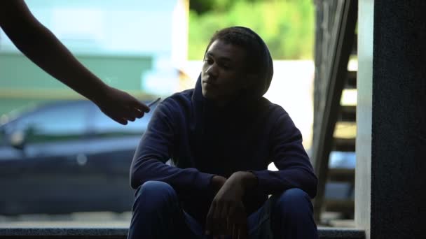 Человек, дающий сигарету с марихуаной грустному бездомному мальчику, подростковой зависимости — стоковое видео