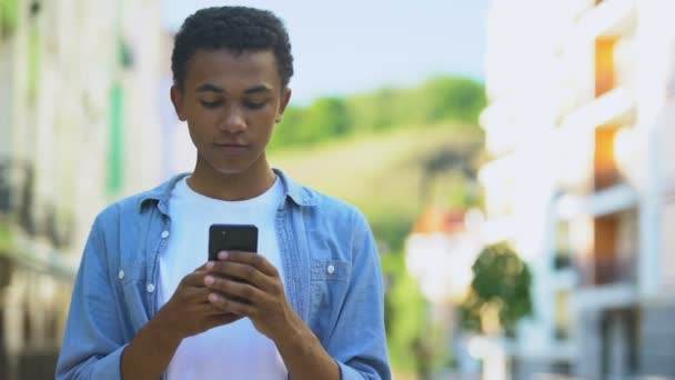 Menino de raça mista chocado com newsletter em seu smartphone, ofertas promocionais — Vídeo de Stock