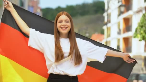 Fröhlicher rothaariger Teenager, der die deutsche Fahne schwenkt und in die Kamera lächelt, Patriotismus — Stockvideo