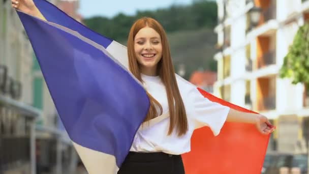 Pyšná fena teen mává vlajkou Francie a usmívá se, národní svátek, sportovní fanoušek — Stock video
